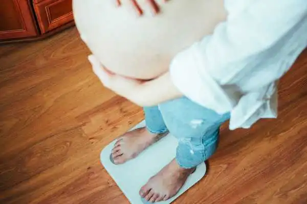 Image of woman weighing herself and experiencing weight gain through pregnancy Welford on Avon